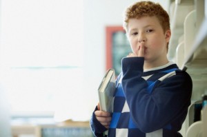 Elementary student making be quiet gesture.